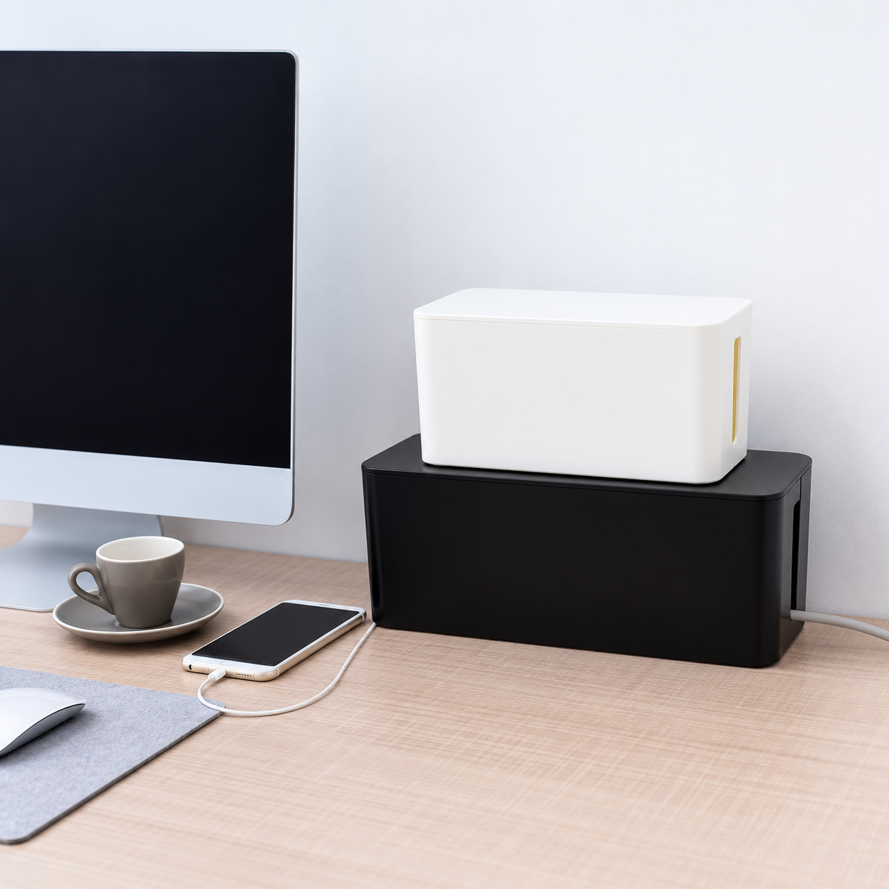 Retouched desk scene with white and black cable boxes beside a monitor